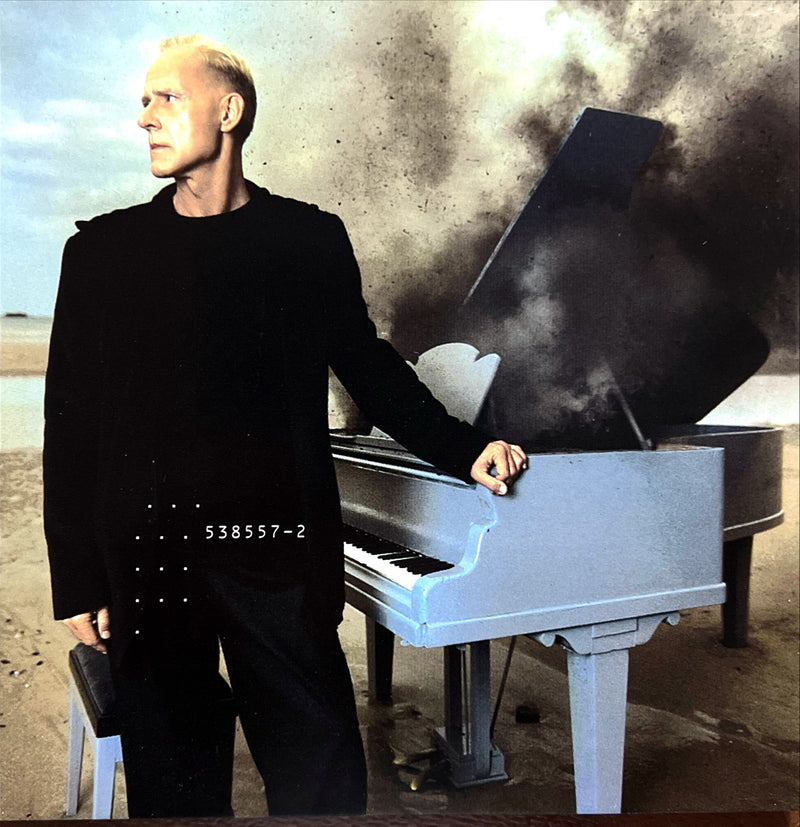 a man standing next to a white piano