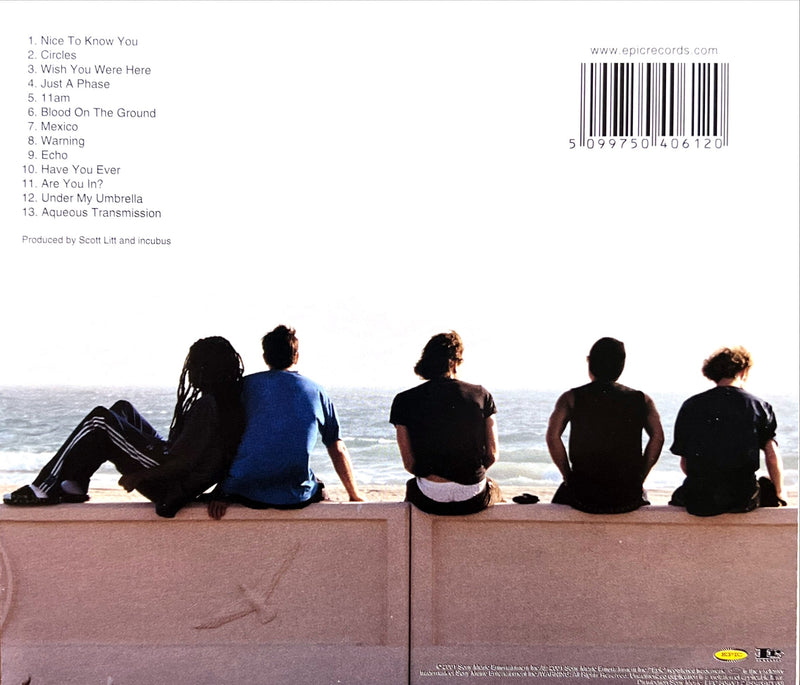 a group of people sitting on top of a wall next to the ocean
